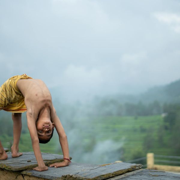 Person sitting in a meditative lotus pose outdoors at sunrise.