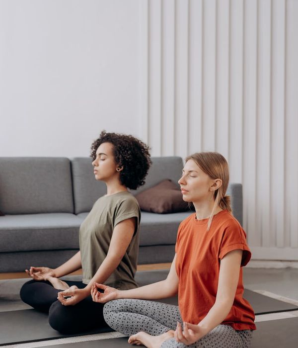 Woman performing a calm yoga pose in a bright, minimalist room.